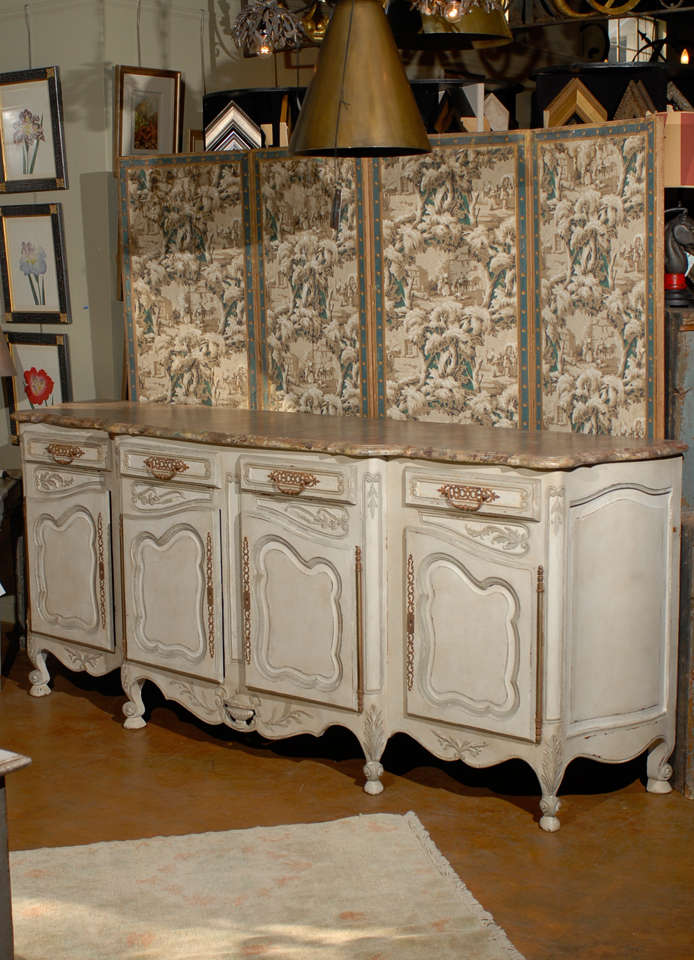 19th century French Provincial paint decorated faux marble top enfidale, the shaped top surmounting an offwhite double door cabinet flanked on either side by a single cabinet all opening to storage and raised on scrolling squat feet. 