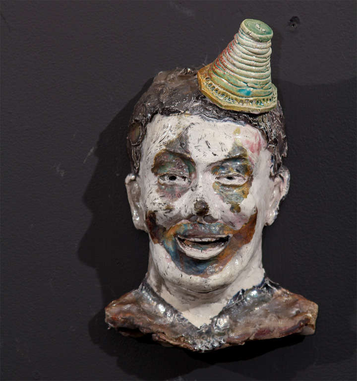 This piece is small but it packs a larger-than-life visual punch.  The glazes selected for this unsigned fired ceramic face are incredible.  The hat is a separate piece which rests upon a post that is inserted into the clown's head.