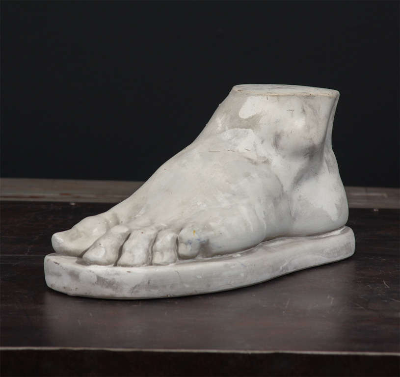Sculpted and unglazed, a big man's foot sculpture on a low-profile riser.