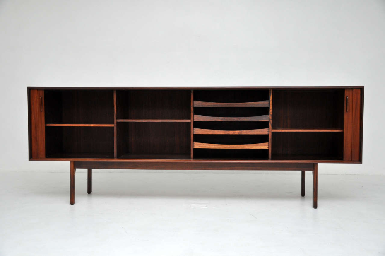 Rosewood sideboard made in denmark.  Tambour doors open to reveal drawers and shelves for storage.  Marked with Danish control label and manufacturer label.  