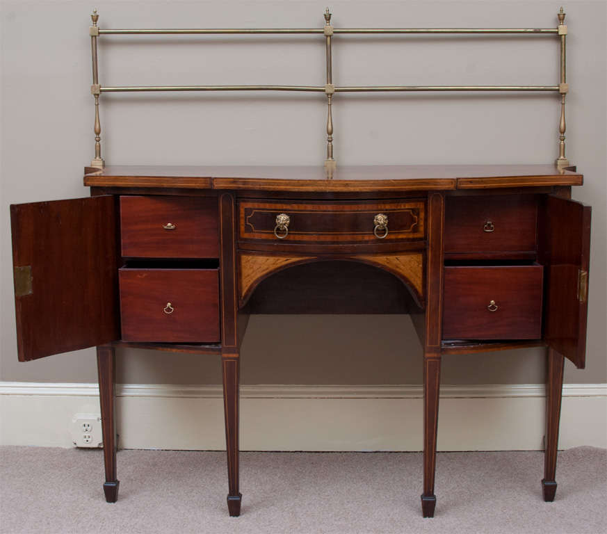 This beautiful English sideboard has a swell front with one center drawer and 2 side doors -- lion head pulls -- the back gallery is original -- behind each door are 2 drawers that were probably added in the 1930s.