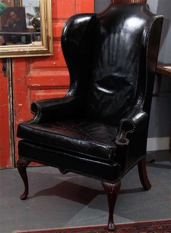 very handsome leather wingback chair in black leather with nailheads and touches of red in seat cushion. good detail-  great lines from all angles