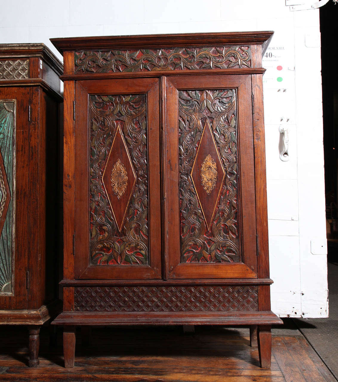 An early 20th century cabinet with detailed carved teak wood from Java, Indonesia. This cabinet adopts a rectangular shape with carved molding on its top and bottom. The two doors feature carved panels with large diamonds surrounded by foliages