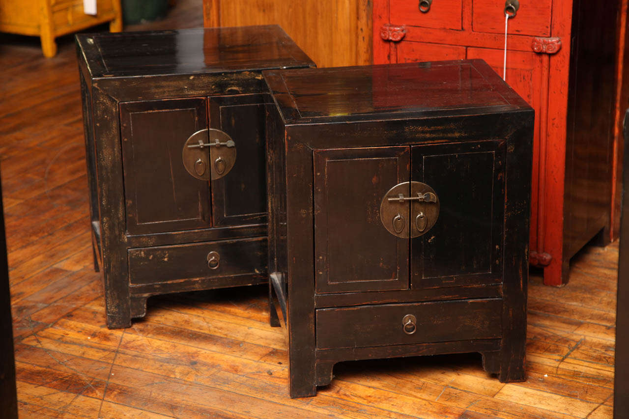 This 19th century pair of bedside cabinets was made with dark brown lacquered elm in China, during the Qing dynasty (17th - 20th century). The linear shape of the cabinets is adorned with a dark brown lacquer which highlights the wood grain and