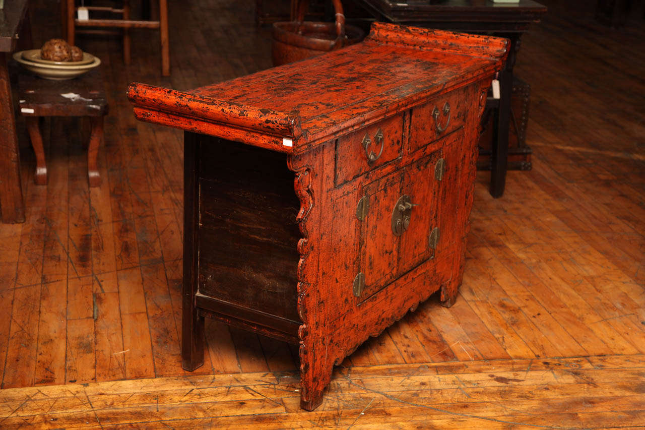 Antique Chinese red sideboard with a distressed finish lacquer.  Everted flanges. Nicely carved.  Round medallion hardware on doors.