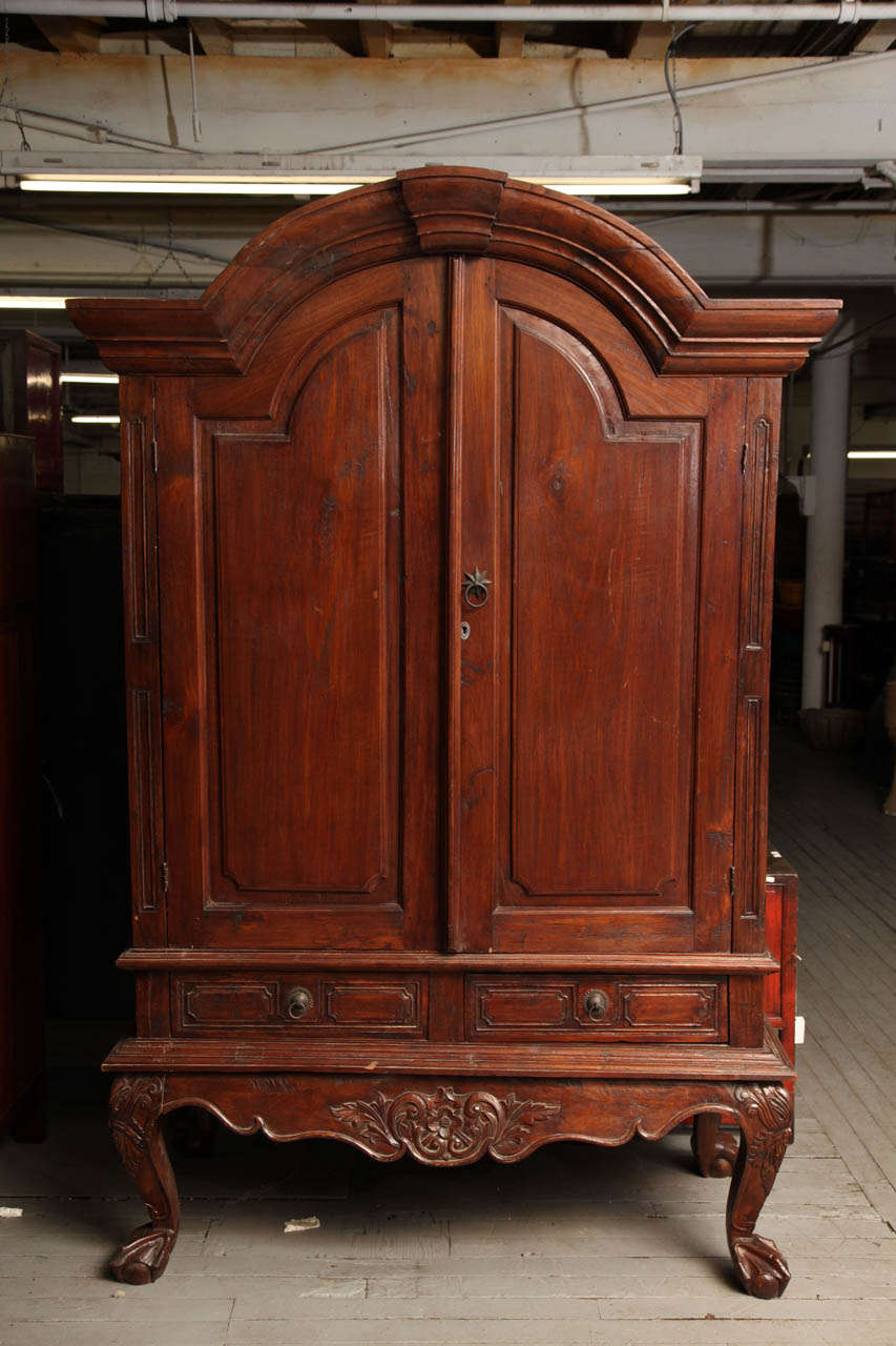 This extra-large palatial armoire was made with teak wood in a Dutch colonial style in Indonesia during the 19th century. It is made with a traditional Indonesian solid teak wood, but showcases Dutch colonial shape and adornments. The armoire