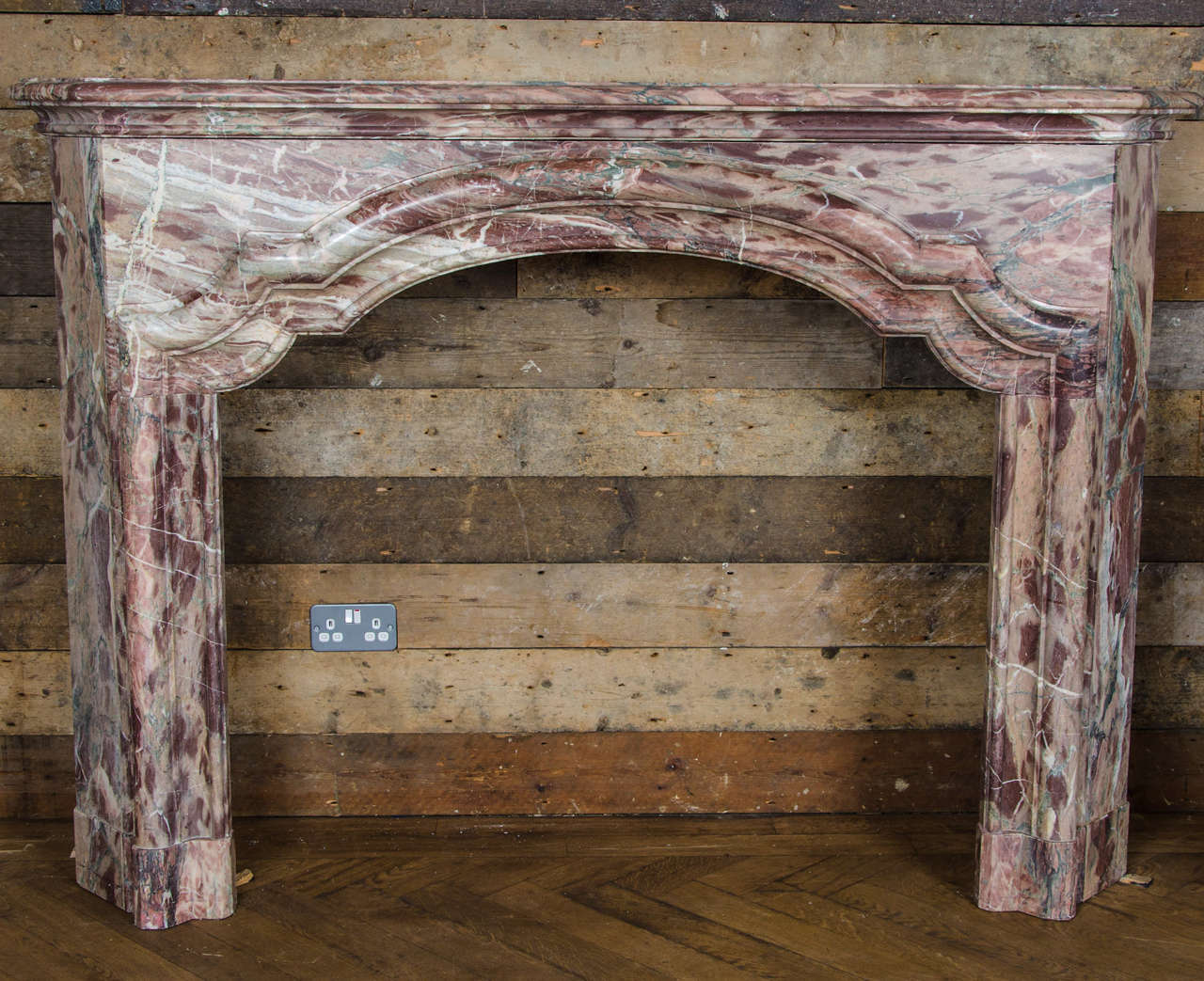 A beautiful antique fire surround in striking Sarancolin marble. This French style surround has a moulded shelf and shaped opening with angled jambs. This surround is made from a distinctive marble with pink and grey veining.