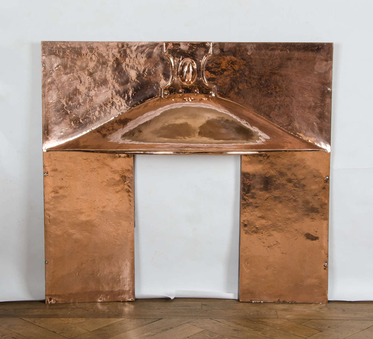 A beautiful original fireplace insert in polished copper. This antique Arts & Crafts insert has a simple design with a sweeping hood and a cartouche motif in the centre. The copper has a hammered finish giving a handmade feel.