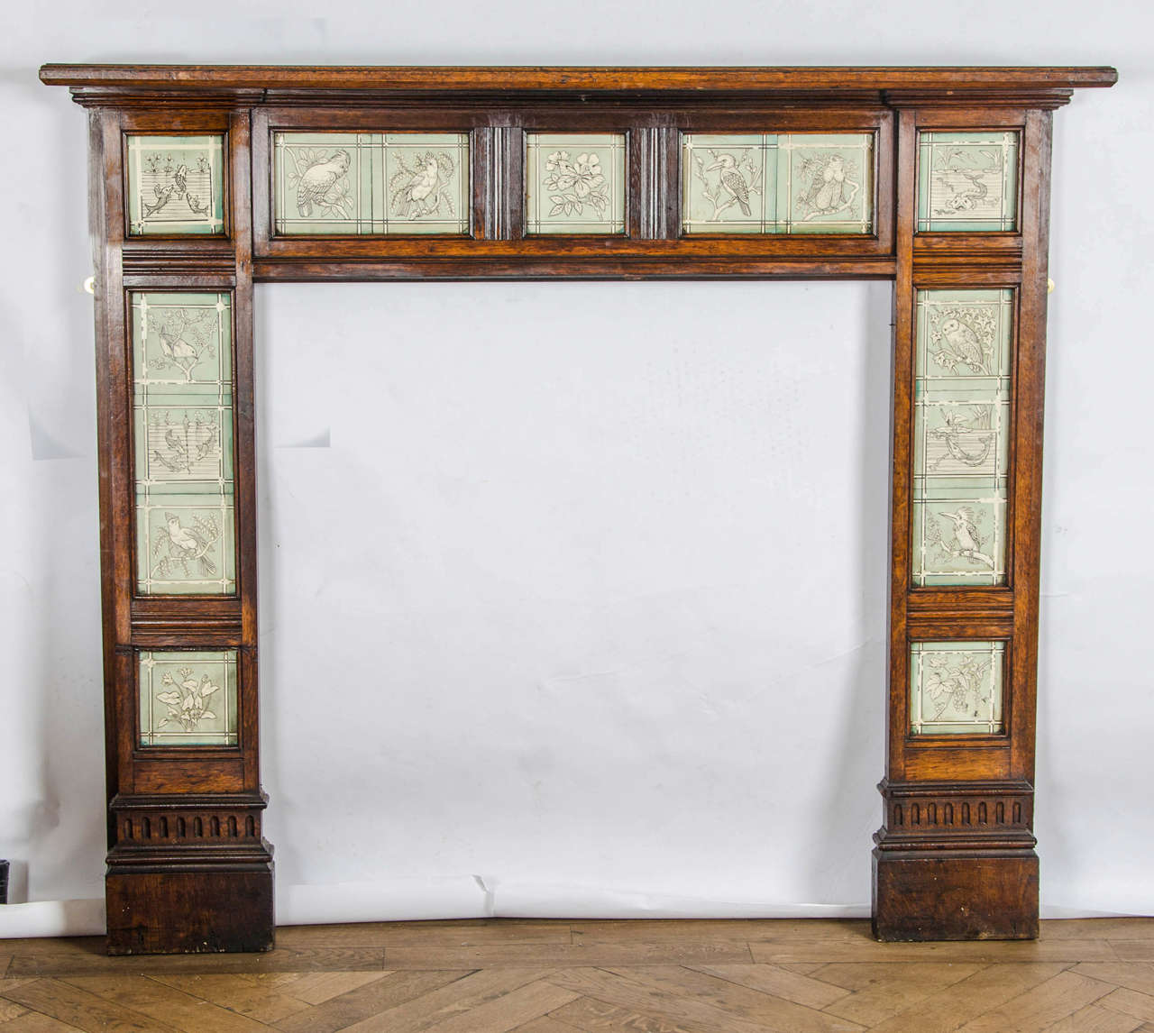 A charming example of a late Victorian Arts & Crafts fire surround in oak. This antique surround is decorated with 15 original Minton tiles which depict illustrations of different wildlife from birds to fish. This is a fantastic Arts & Crafts piece