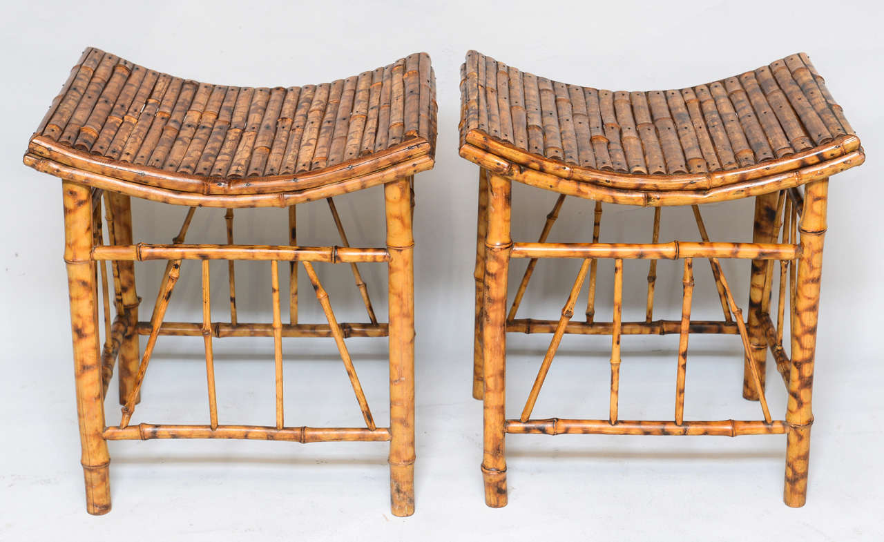 Pair of Victorian stools of burnt bamboo, in the Thebes style, having concave seats, raised on bamboo legs with fretwork stretchers.