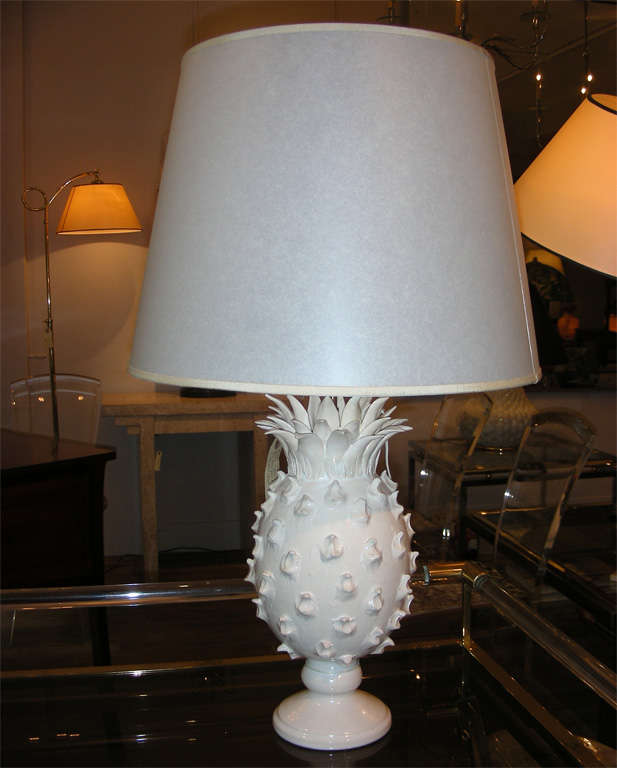 A white ceramic lamp in the shape of a stylised pineapple, complete with leaves and small pedestal. Signed: « Jean Roger Paris France pour Marcus ». Sold with a white translucent lampshade.