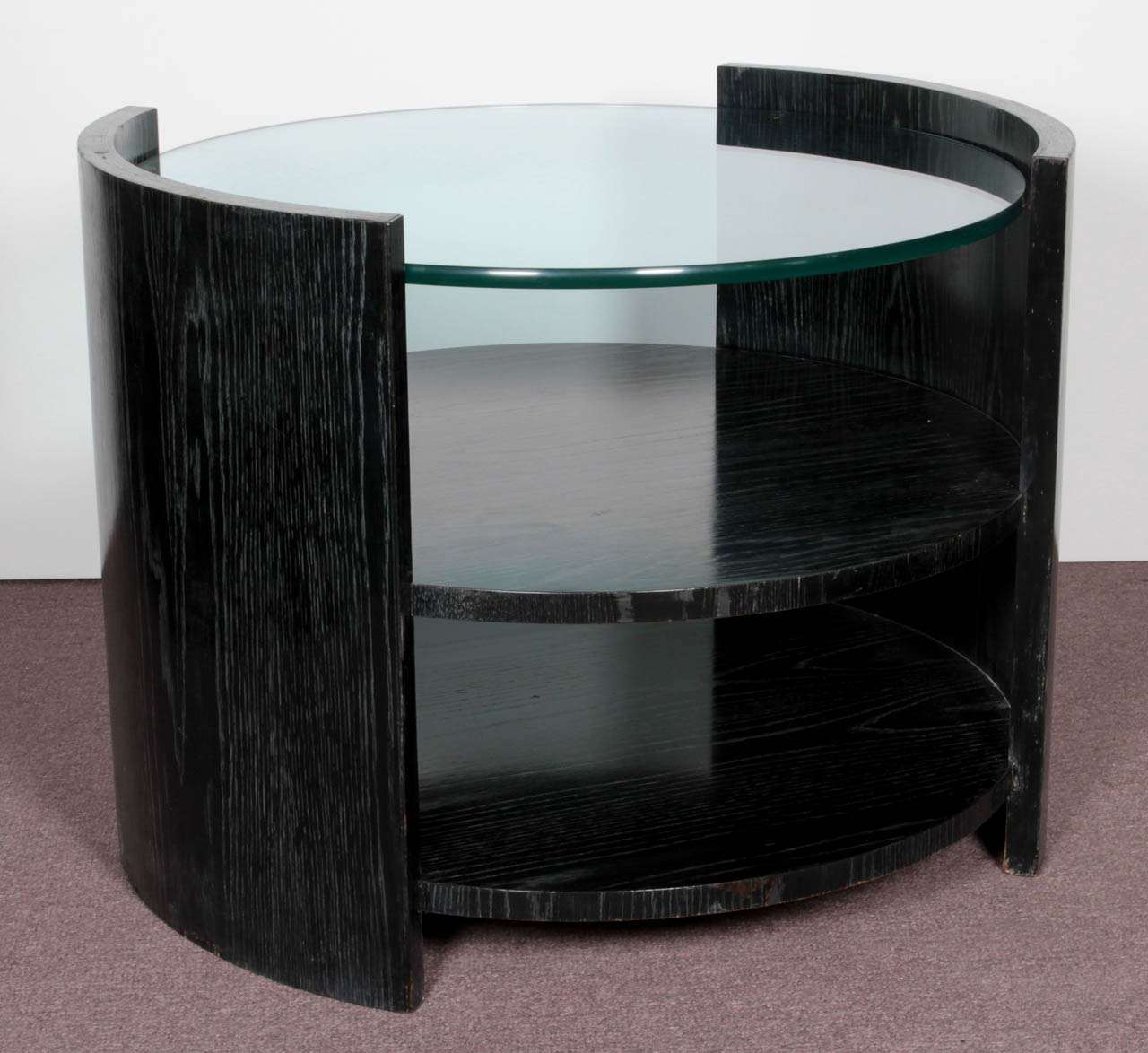 A large limed, blackened oak barrel side table by Jay Spectre of eclipse design, tiered with three practical surfaces and topped by a heavy 5/8” thick circular glass. Store your newspapers/ magazines, your trinkets or keep it clean and simple on