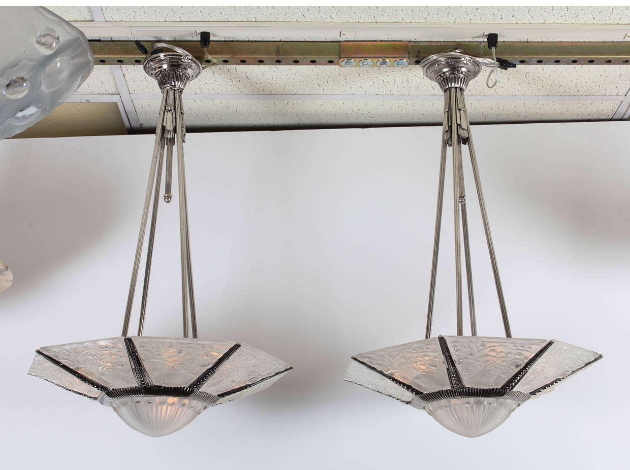 A pair of elegant French Art Deco chandeliers by Leleu comprising eight panels plus the center. A central coup in molded, frosted art glass decorated in radiating stripes with ball border is surrounded by eight trapazoid shaped frosted art glass