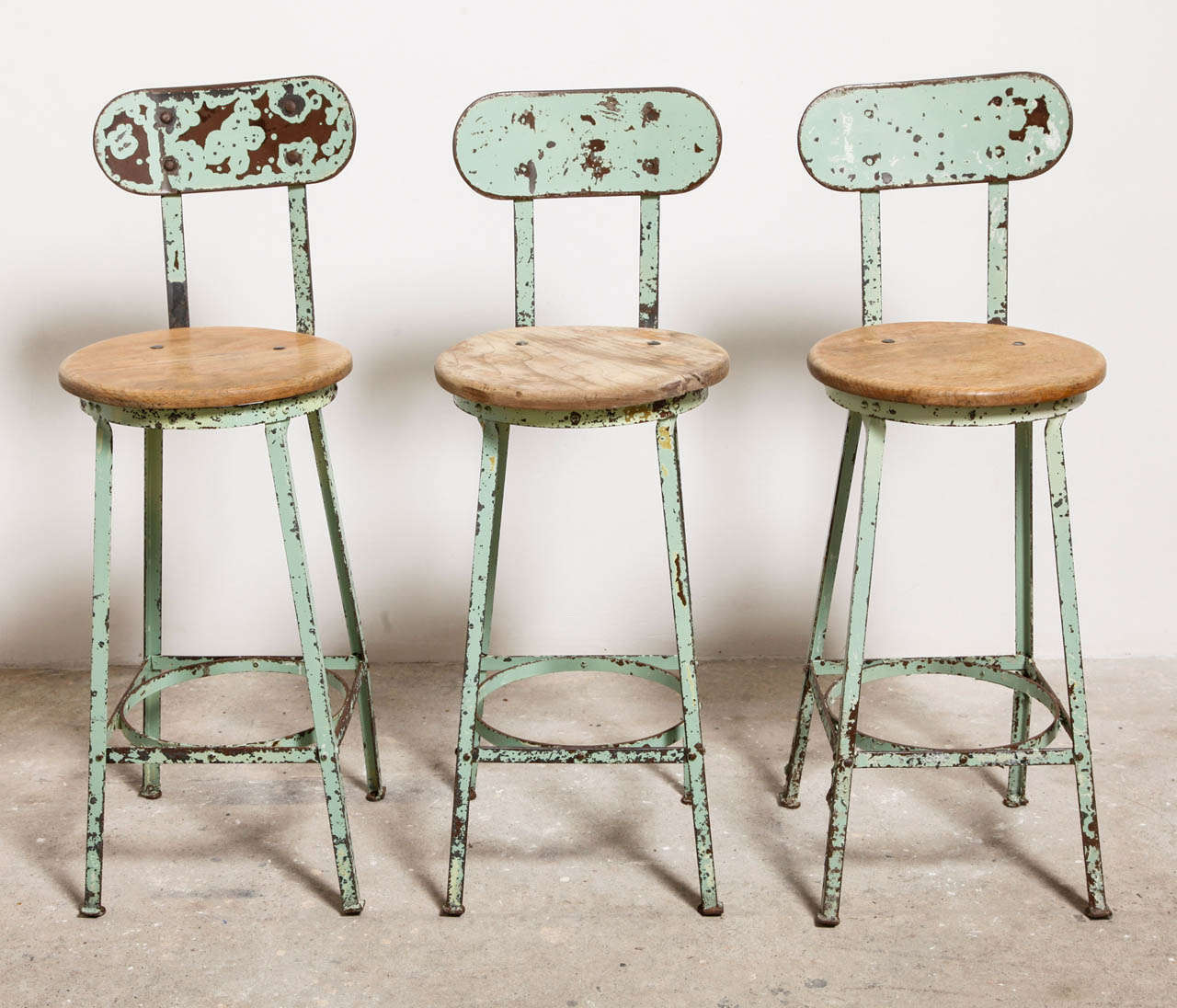 Industrial bar stools, strong and sturdy circa 1930s heavy gauge cold-rolled steel four-legged angled steel factory stool with wooden seat.