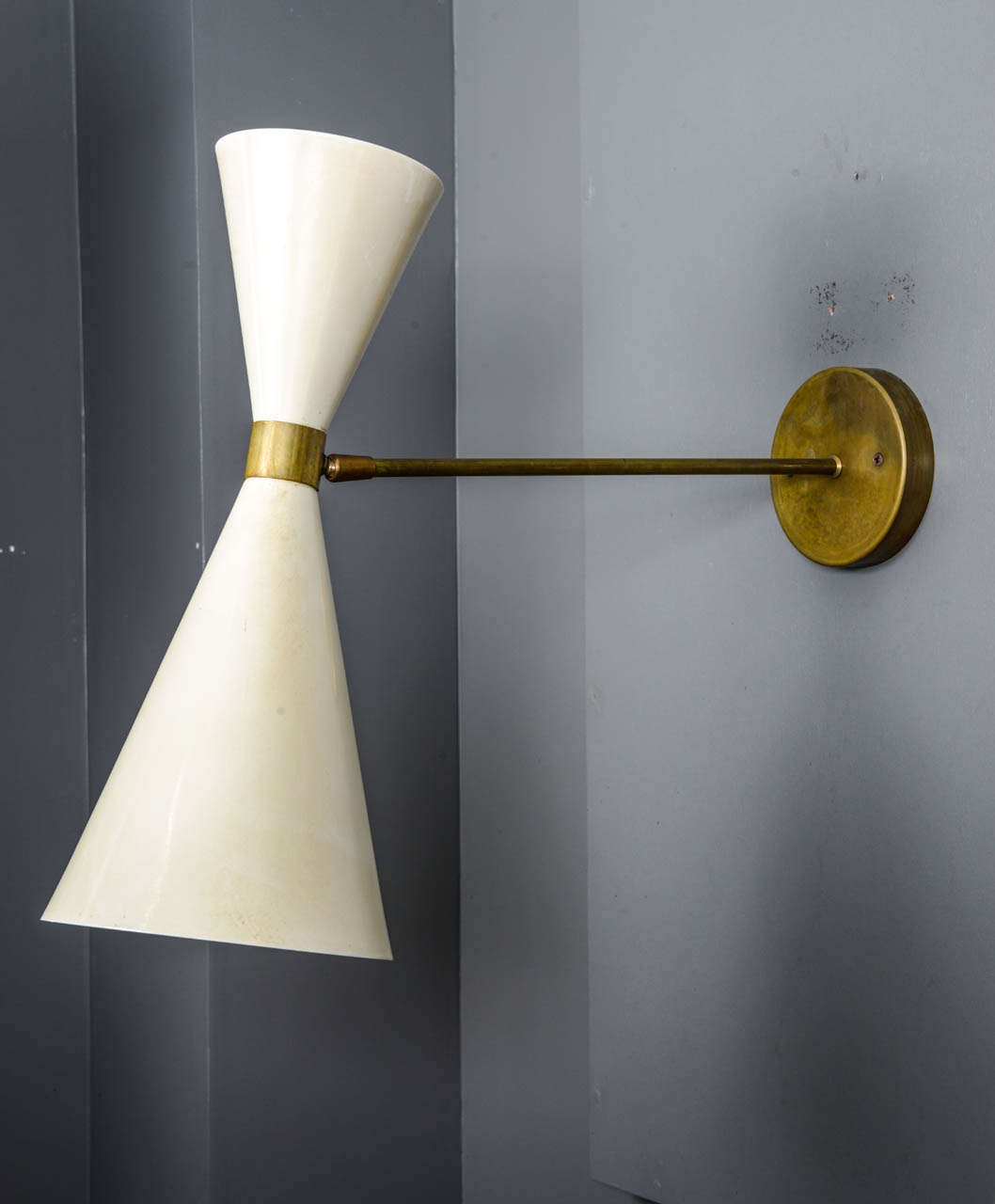 Set of four wall sconces designed by Stilnovo in the 1960s.
Made of a brass arm and two white enameled metal cones.

Two lights per sconces, new electrification.