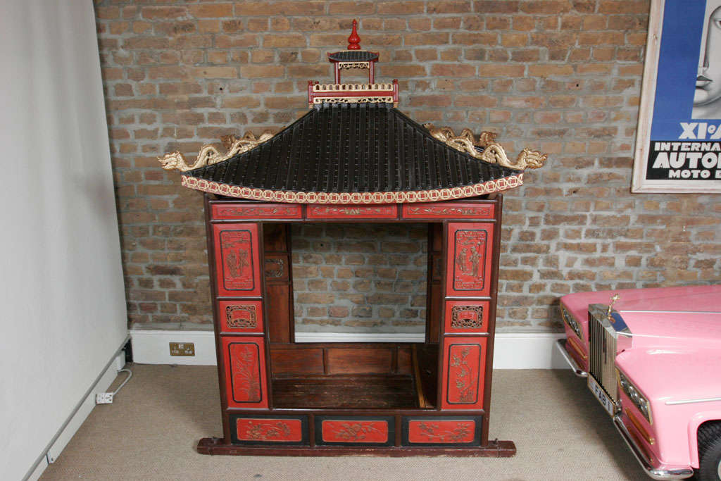 Traditional Chinese bridal sedan chair painted in typical Chinese red and gold with intricately carved detail.