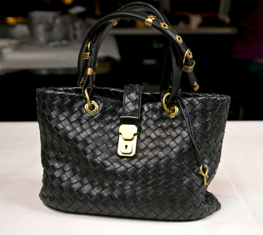 funkyfinders brings you this high-style signature black woven leather satchel by bottega veneta. the brass accents are noteworthy. a brass lock and key enhance the purse's panache. the suede interior boasts a main compartment, zippered area, and