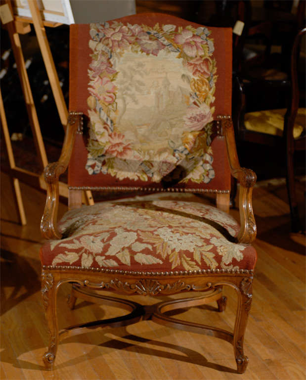 This is a lovely French Walnut and needlepoint arm chair.  The scroll carvings and x-base stretcher add to the beautiful details for this chair.  The petit point needlework has a castle image and is framed with trees and flowers.  The colors are