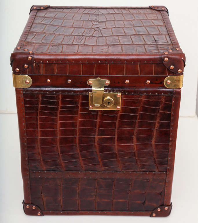Large decorative trunk recovered in a turn of the century crocodile skin. The crocodile is a dark mahogany shade with exceptional quality and patterning. The trunk is decorated with brass studs, reinforced corners and heavy duty handles on both