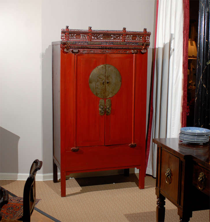 This beautifully red lacquered wedding cabinet is made of pine. This was created in the Zhegiang on the East Coast of China. The hardware is original and the carved bonnet on top is quite rare in today's market.