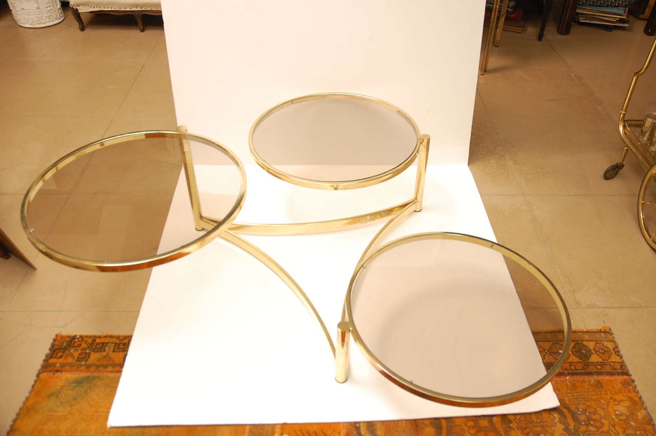 1970's 3 circle brass and glass tiered swivel coffee table. Triangle shaped brass base. 