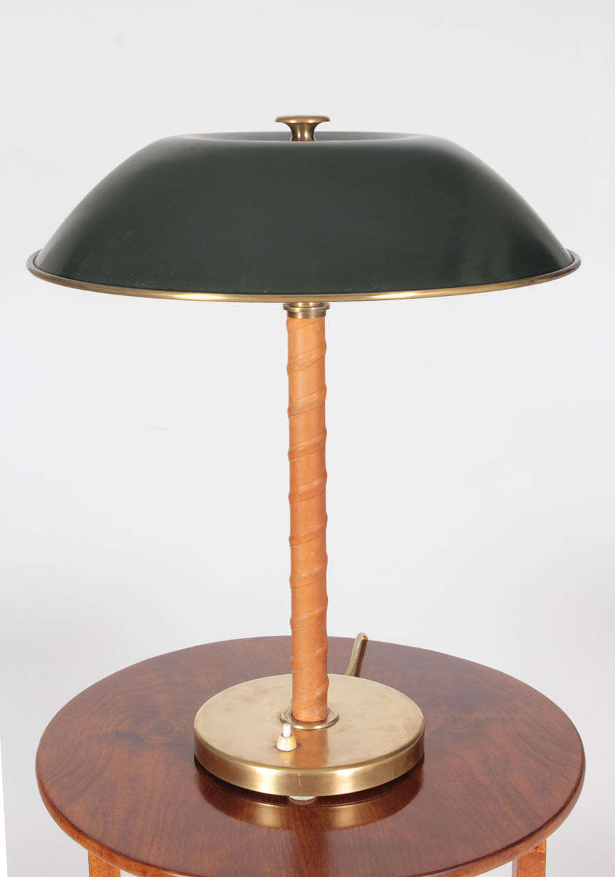 A Swedish Modern table lamp, with a green painted dome shape shade, leather wrapped stem and circular brass base. Probably made by Einar Bäckström Metallvarufabrik, Malmo. or Zenith Rewired to US specs.