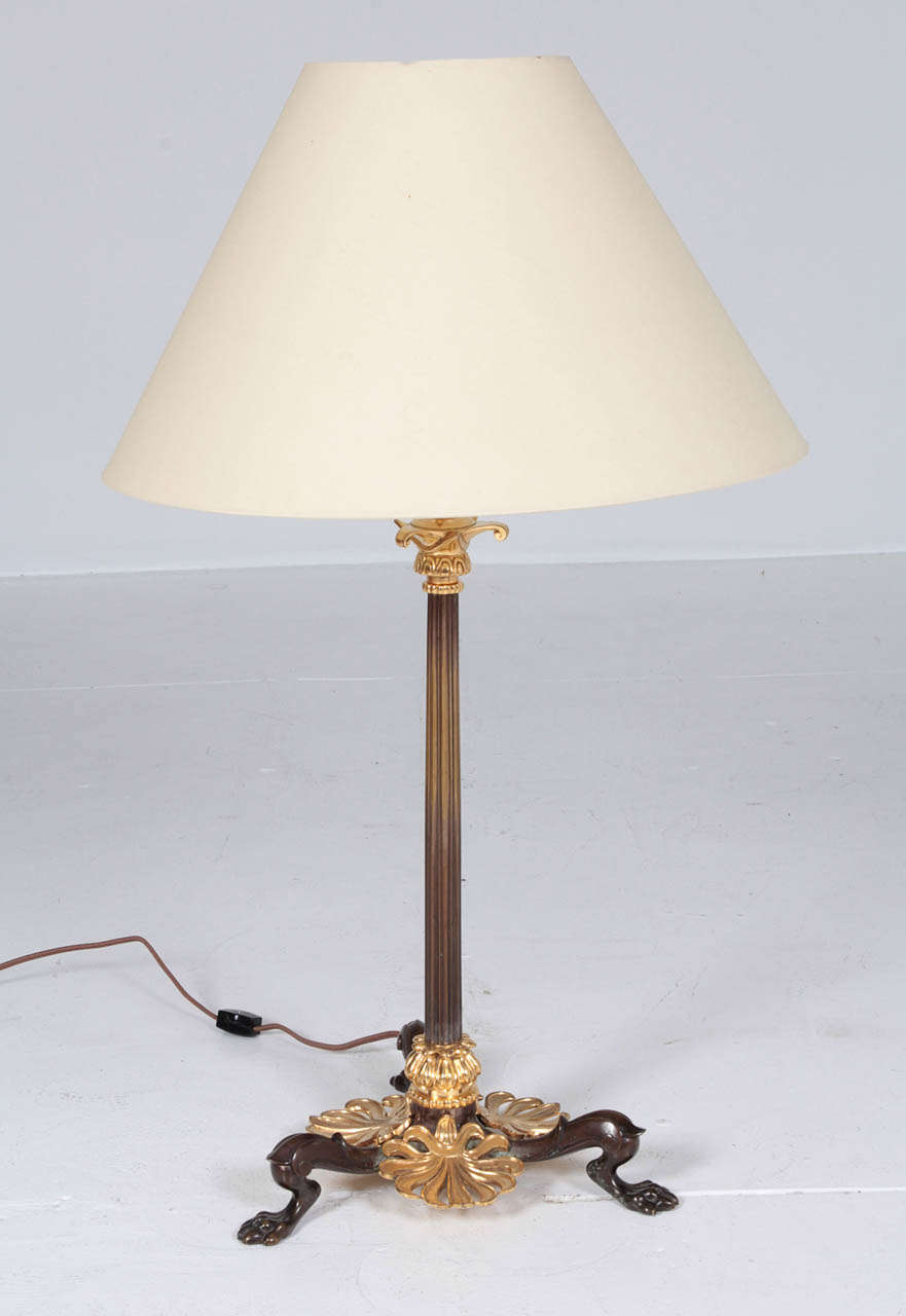Danish table lamp designed by the architect Michael Gottlieb Bindesbøll (br.1800 died 1856)  Mid 19th Century, fire gilded bronze and patinated bronze, with a reeded stem raised a on tripod base with anthemion leaves and animal paws. Converted from