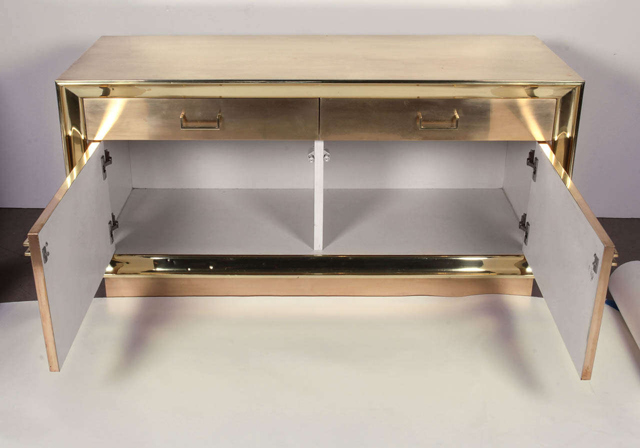 Brass veneered to a wooden core covers the fronts, tops and sides of these cabinets, which have a white lacquer interior. Soft hand-polished finish has a warm color, accented by a highly polished and lacquered 