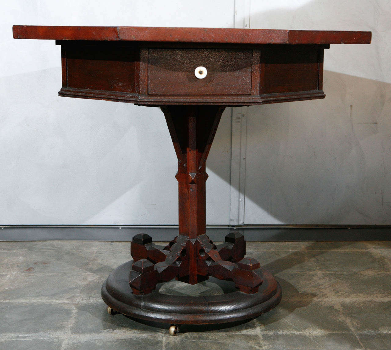 A most unusual and interesting American, 19th century, table having an octagonal top, recessed skirt with two drawers, on a central column which stands on a circular base with wheels. The top has a mysterious and intriguing panel veneered in exotic