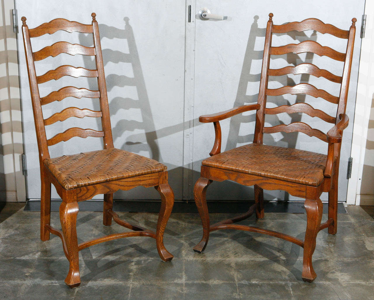 This charming set of dining chairs with: out turned legs, shaped stretchers, unique woven split oak seats and tall pleasing designed ladder backs. This set is thought to be French and has two arm and four side chairs. The set will suit a variety of