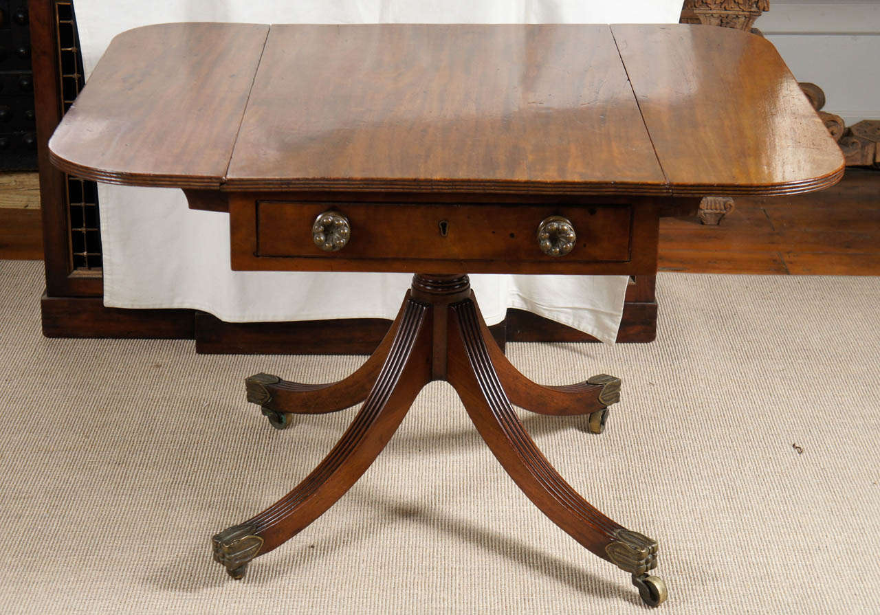 Fine George III solid mahogany side/ breakfast table. Top with reeded edge and two flaps over one drawer raised on four downswept legs. Brass cap toes and casters. Later brasses to the drawers.