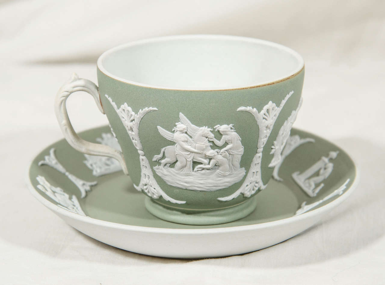 A Wedgwood jasperware tea cup and saucer with a neoclassical design sprigged in white showing mythological figures in applied bas-relief on an olive-green dip ground. The curved graceful handle adds to the beauty of this cup and saucer.
Wedgwood