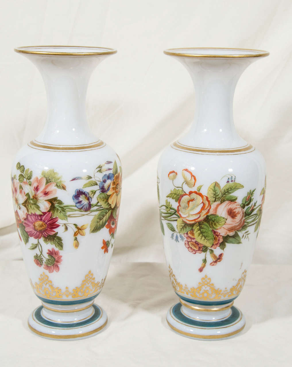 A pair of opaline vases with beautifully painted bouquets of hand-painted flowers. The glass is slightly translucent, handblown and without seams. Opaline is a decorative style of handblown glass made in France beginning, circa 1800.