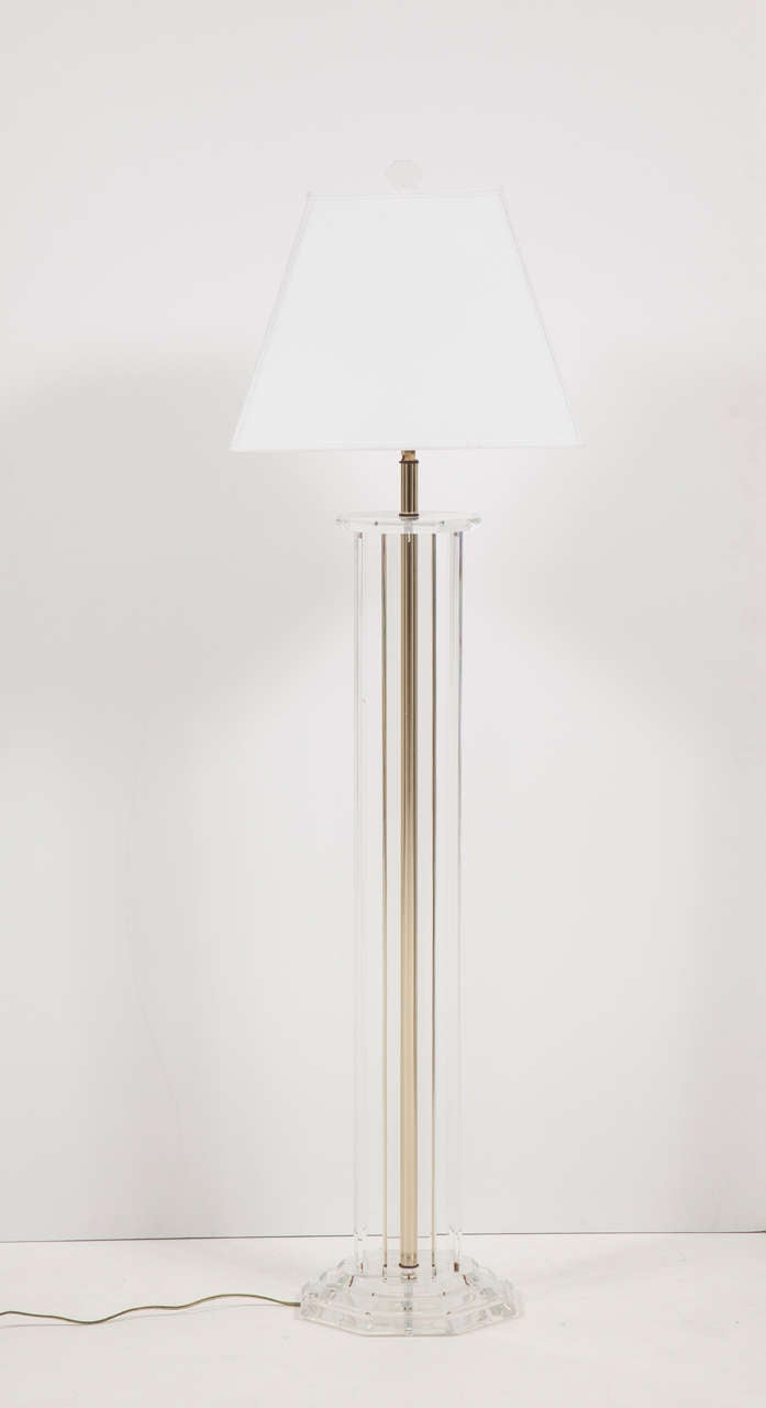 A sleek floor lamp in Lucite and brass with a graduated base.