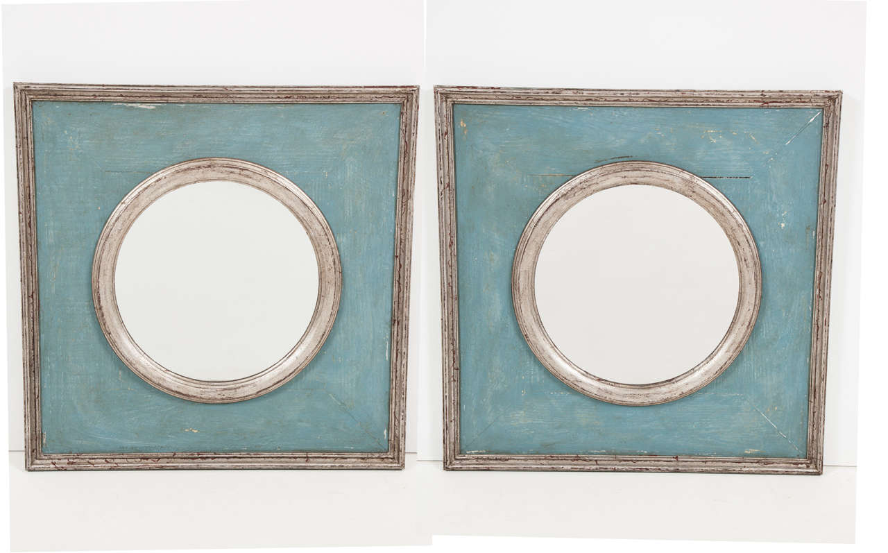 A pair of mirrors of our design, made in France with reclaimed wood. The inner molded circle surrounding the mirror and the outer molded frame are silvered. The area surrounding the mirror is painted in a deep blue. With their clean lines, these
