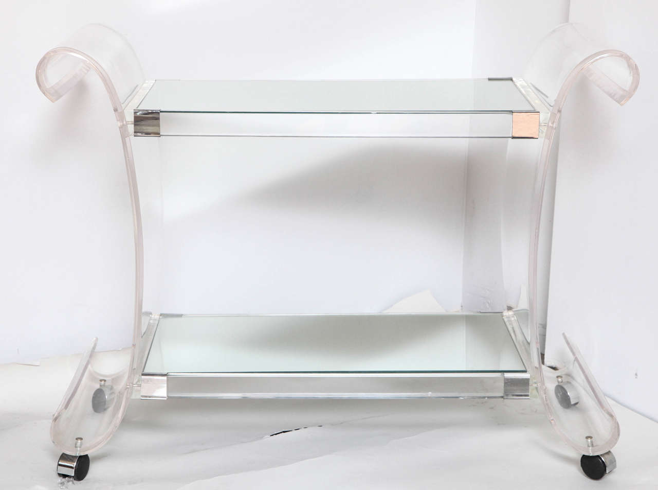 A fabulous bevelled Lucite bar cart with two mirrored shelves on four easy pull chromed wheels.