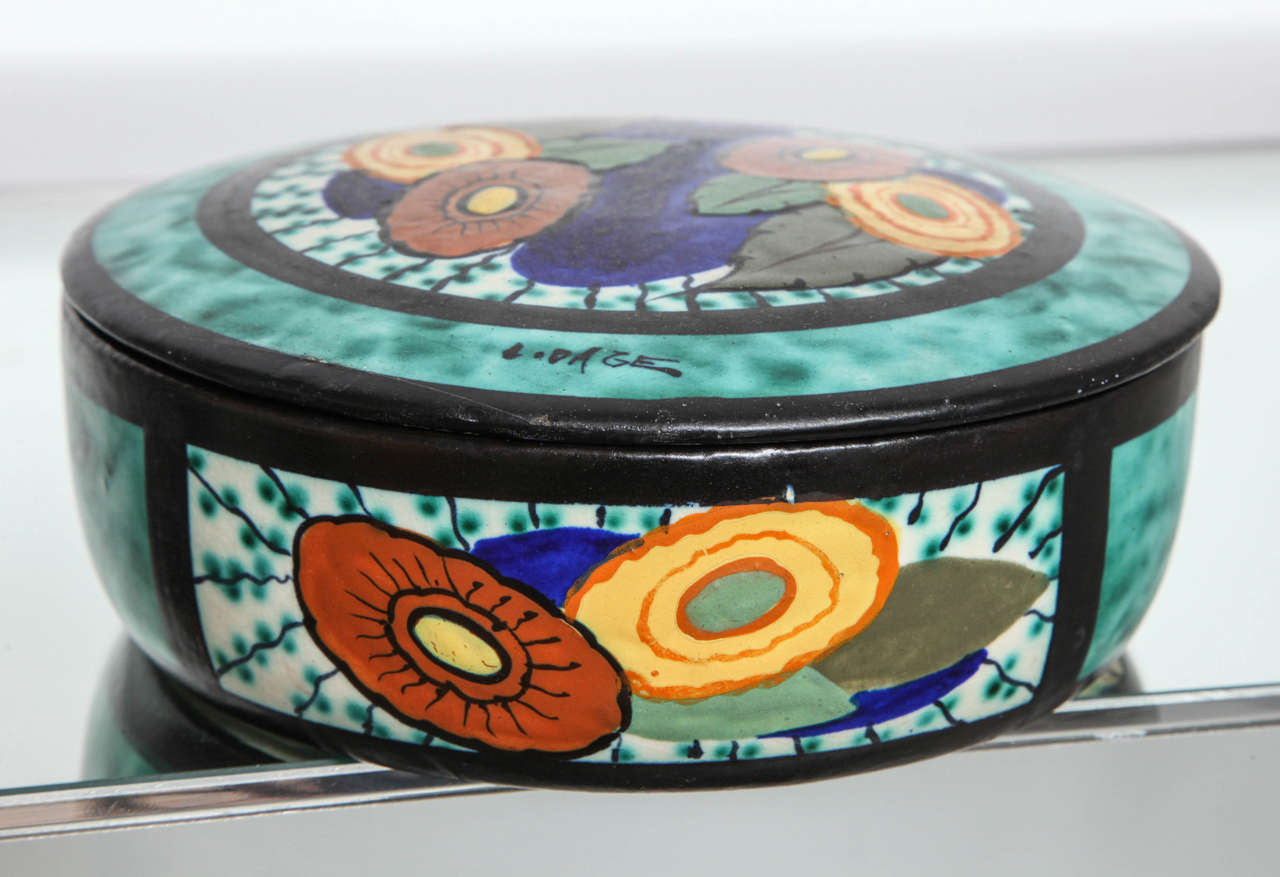 A colorful hand-painted lidded ceramic box depicting an Art Deco abstracted floral decoration by Louis Dage.