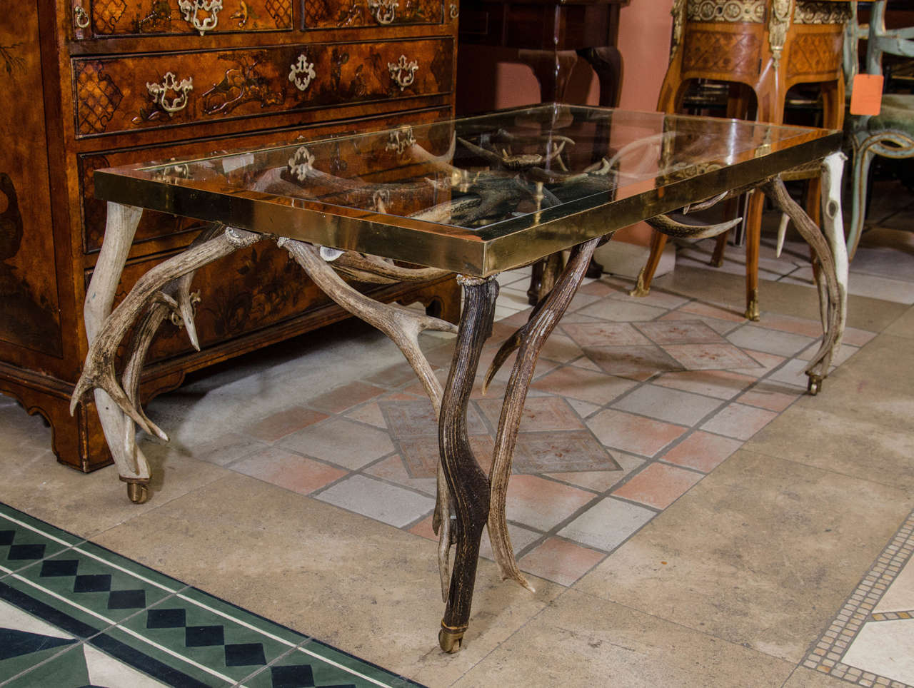 A rustic coffee table with deer-antler base and brass-bound glass top.