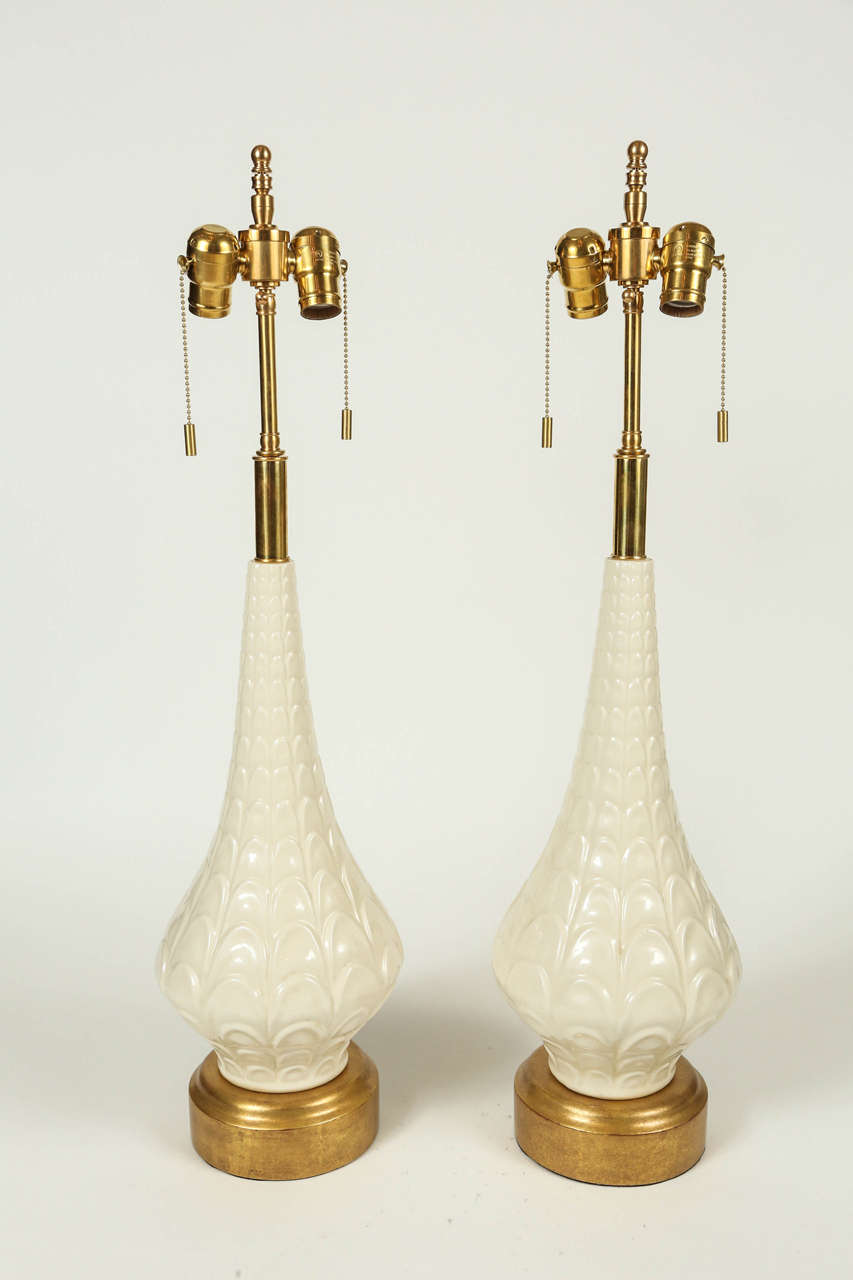 Pair of Danish Mid-Century Modern sculptural white pottery lamps. Features giltwood base, brass pulls and finial, and silk wrapped cord. Newly wired with down lights, takes two standard bulbs.