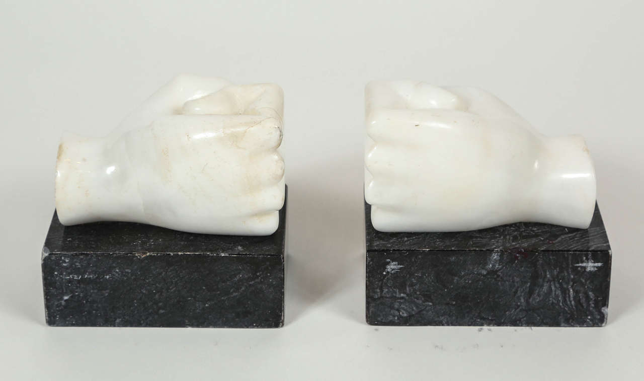 Pair of vintage alabaster fists bookends on black stone plinths.