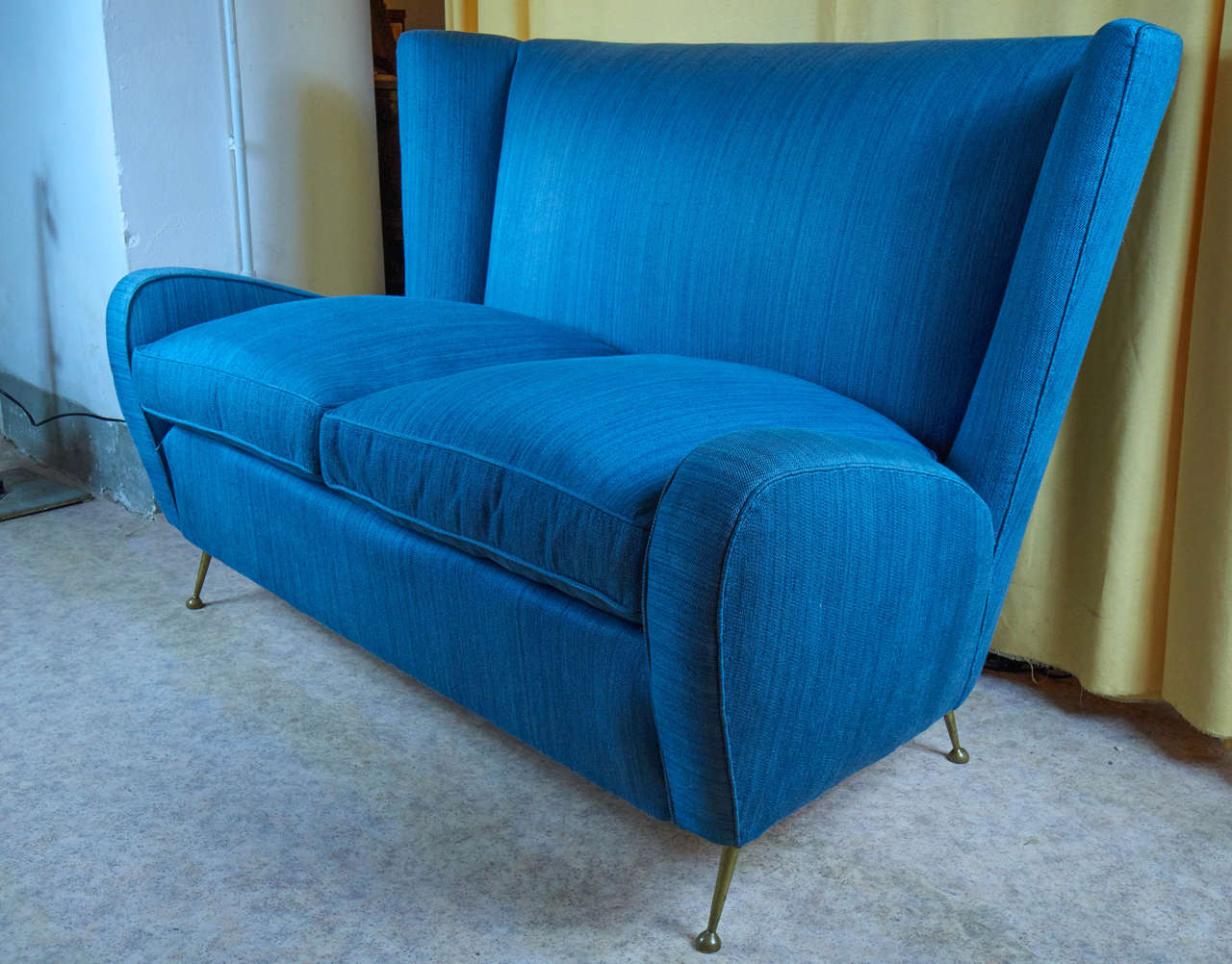 Interesting shaped 1950s sofa with four cast bronze thin legs.
 Upholstered original cotton bleu fabric.