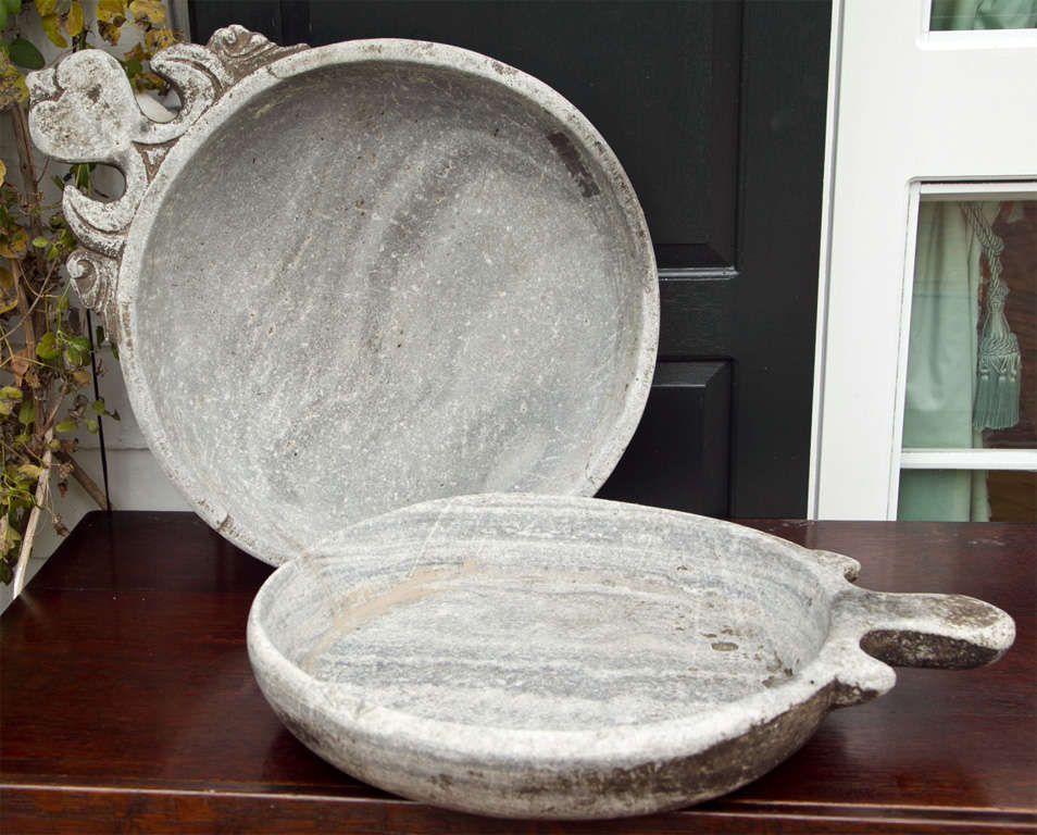 Two grey marble dishes with flat decorated handles. <br />
<br />
This type of dish was used in India for the purpose of mixing foodstuffs. This particular form, produced primarily in India, but closely related to dishes in Afghanistan and