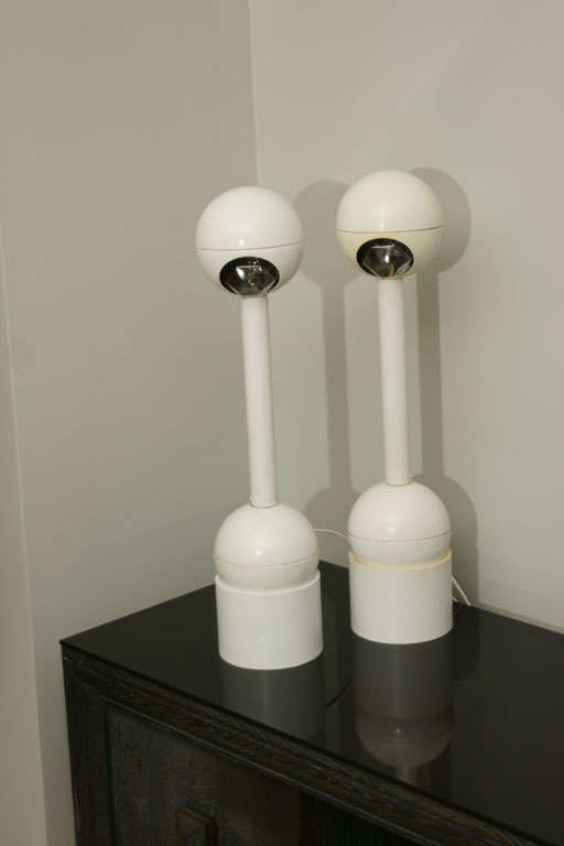 A Great pair of Barbell lamps designed by John Mascheroni. The metal lamp bodies sit on cylinderical bases and are turned on / off by moving the lamp forward and back on their bases.