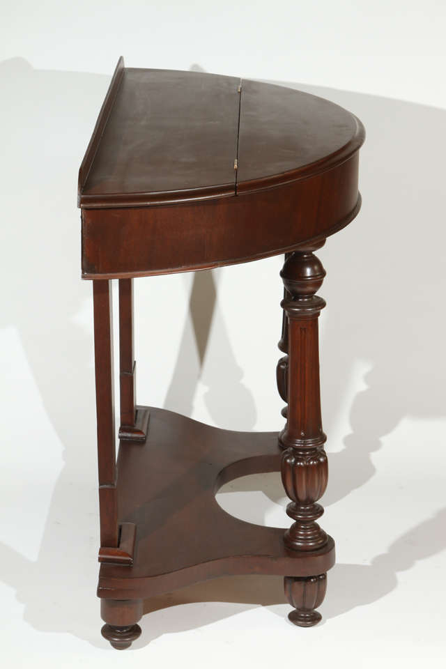 1940s half circle mahogany side table with turned front legs and top storage compartment. Fully refinished.
