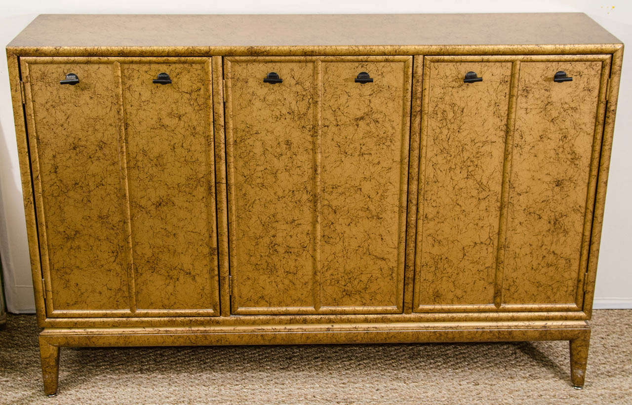 A small credenza in a faux gold finish with three doors.  Perfect for a small entry or room.