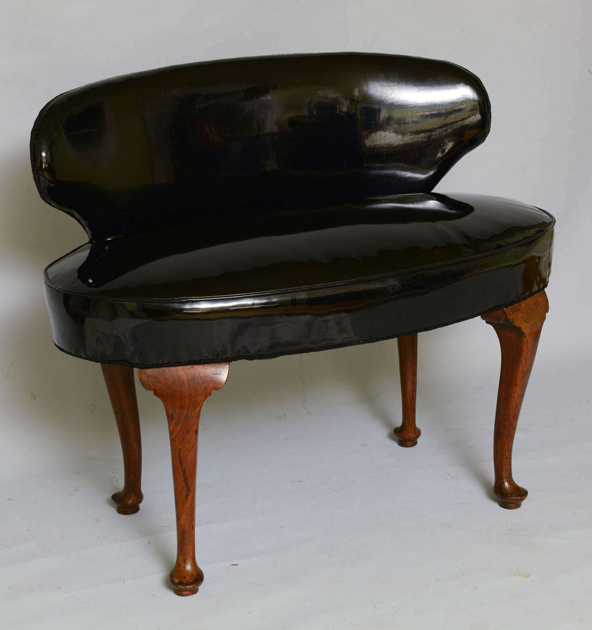 Antique settee, having curved backrest and oval seat, vintage upholstery black patent leather/vinyl, raised on walnut cabriole legs with pad feet.

We are pleased to assist you by obtaining shipping quotes on your behalf.