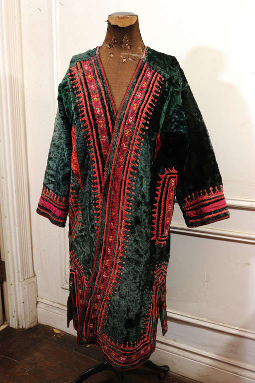 The Kaftan is made of crushed dark green velvet, elaborately decorated with applications of red silk and embroideries. The right side has a pocket and around it the opening has more detailing then the left. It's a real work of art.
