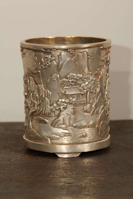 Chinese silver gilt bronze bitong, or brush pot. Of cylindrical form supported on three bracket feet, the exterior cast in relief with continuous design or scholars, courtiers and attendants in a mountainous landscape with bridge and pavilions. The