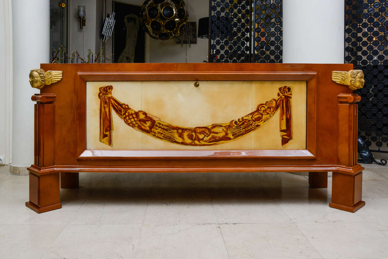 Spectacular sideboard or dry bar from the 1940s by Andre Arbus.
All in oak with a caramel light lacquer. 
The front door covered in parchment painted of a gold motif opens the way down and can be used as a bar.
The inside is also in oak.
Two