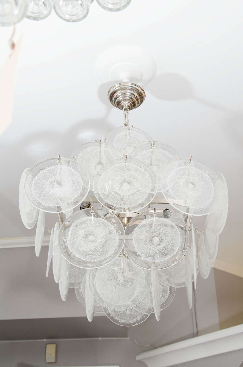 Small clear bubble Murano glass disc chandelier in double pyramid shape. The frame is in polished stainless steel finish. Customization is available in different sizes, finishes and glass colors.